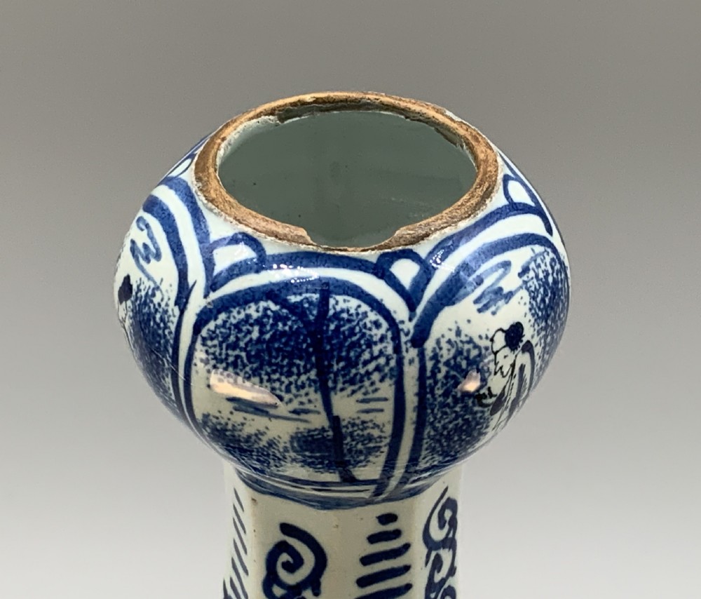 A tall, octagonal blue and white tin-glazed earthenware vase featuring a garlic bulb neck and hand-painted Chinoiserie scenes within arched panels. View IX