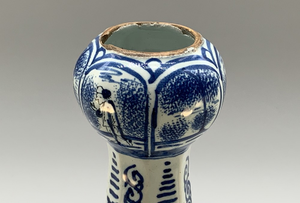 A tall, octagonal blue and white tin-glazed earthenware vase featuring a garlic bulb neck and hand-painted Chinoiserie scenes within arched panels. View XI