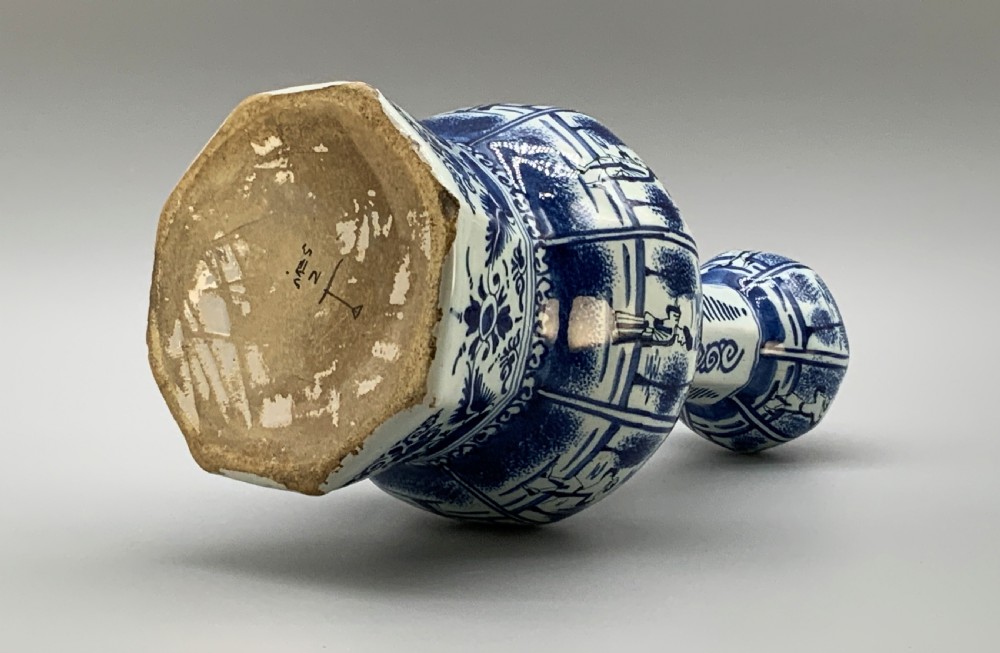 A tall, octagonal blue and white tin-glazed earthenware vase featuring a garlic bulb neck and hand-painted Chinoiserie scenes within arched panels. View XII