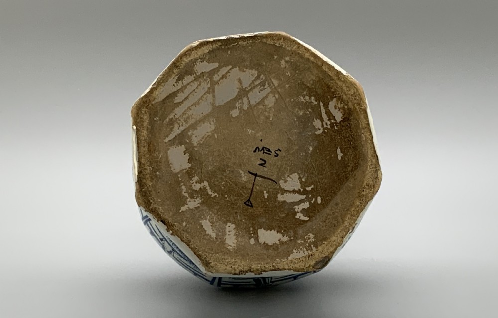 A tall, octagonal blue and white tin-glazed earthenware vase featuring a garlic bulb neck and hand-painted Chinoiserie scenes within arched panels. View XIII