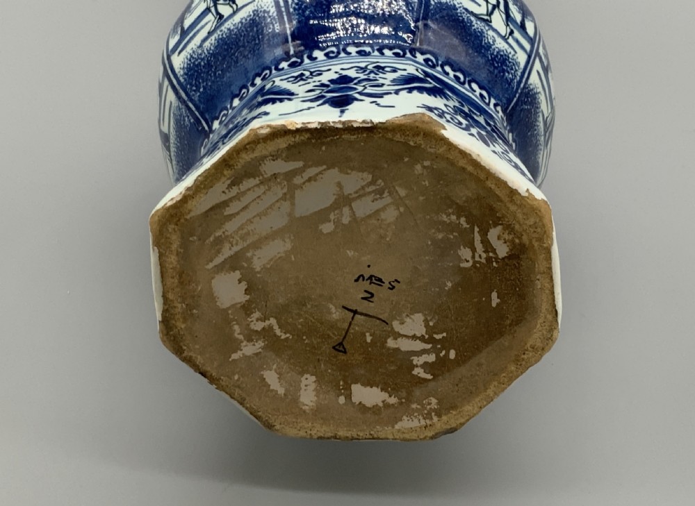 A tall, octagonal blue and white tin-glazed earthenware vase featuring a garlic bulb neck and hand-painted Chinoiserie scenes within arched panels. View XIV