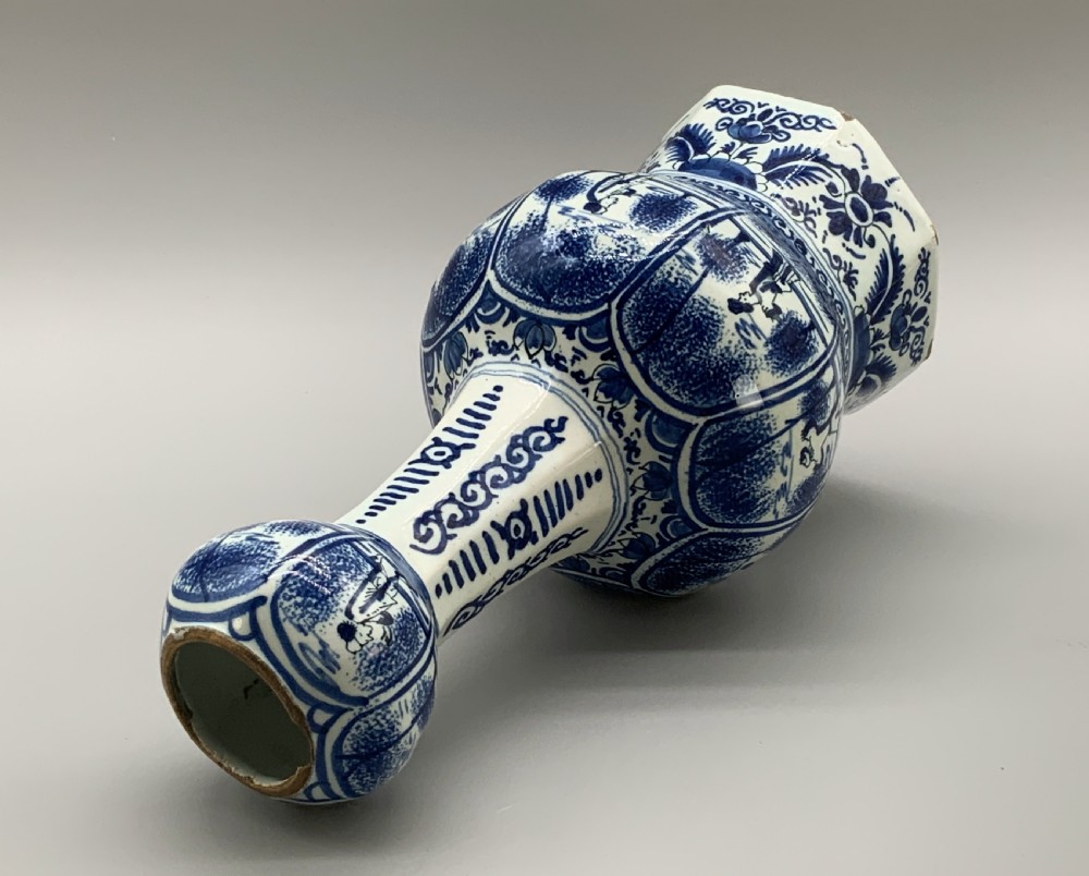A tall, octagonal blue and white tin-glazed earthenware vase featuring a garlic bulb neck and hand-painted Chinoiserie scenes within arched panels. View XV