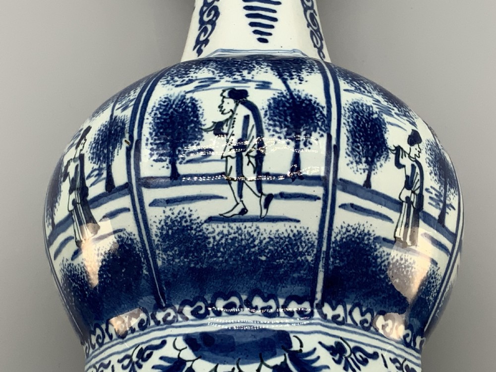 A tall, octagonal blue and white tin-glazed earthenware vase featuring a garlic bulb neck and hand-painted Chinoiserie scenes within arched panels. View XVII