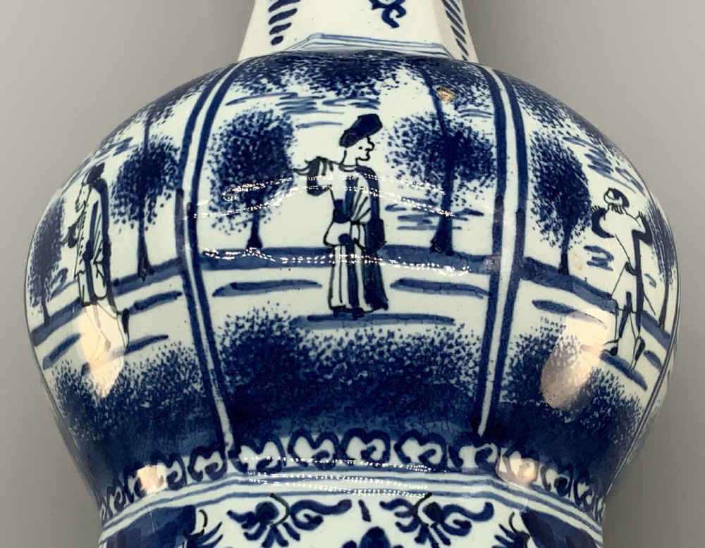 A tall, octagonal blue and white tin-glazed earthenware vase featuring a garlic bulb neck and hand-painted Chinoiserie scenes within arched panels. View XVIII