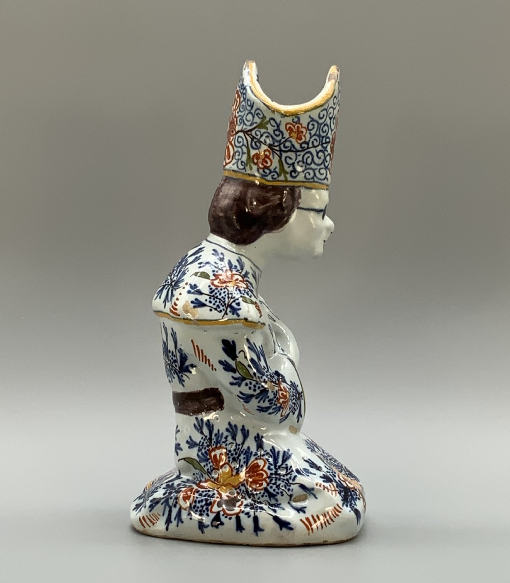 An 18th-century Dutch Delftware ceramic candlestick formed as a kneeling bishop in patterned robes and a mitre decorated with polychrome glazes. View VII