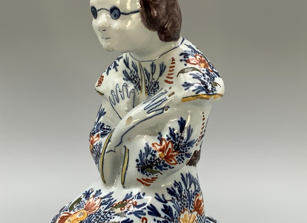 An 18th-century Dutch Delftware ceramic candlestick formed as a kneeling bishop in patterned robes and a mitre decorated with polychrome glazes. View X