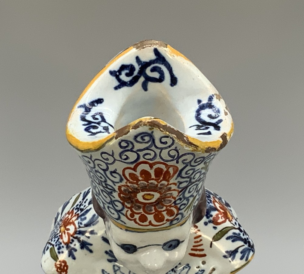 An 18th-century Dutch Delftware ceramic candlestick formed as a kneeling bishop in patterned robes and a mitre decorated with polychrome glazes. View XIII