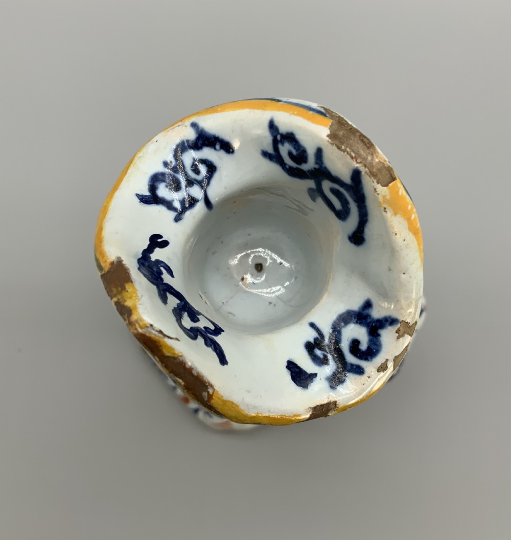An 18th-century Dutch Delftware ceramic candlestick formed as a kneeling bishop in patterned robes and a mitre decorated with polychrome glazes. View XIV
