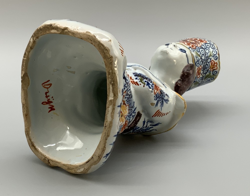 An 18th-century Dutch Delftware ceramic candlestick formed as a kneeling bishop in patterned robes and a mitre decorated with polychrome glazes. View XV
