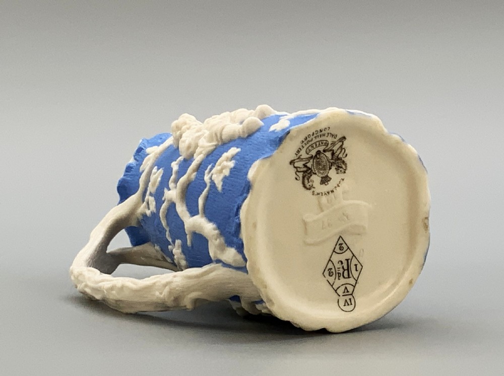 A Victorian blue and white Parian ware jug featuring a textured cobalt blue ground with raised white relief figures climbing a tree and a moulded branch handle. View XIV
