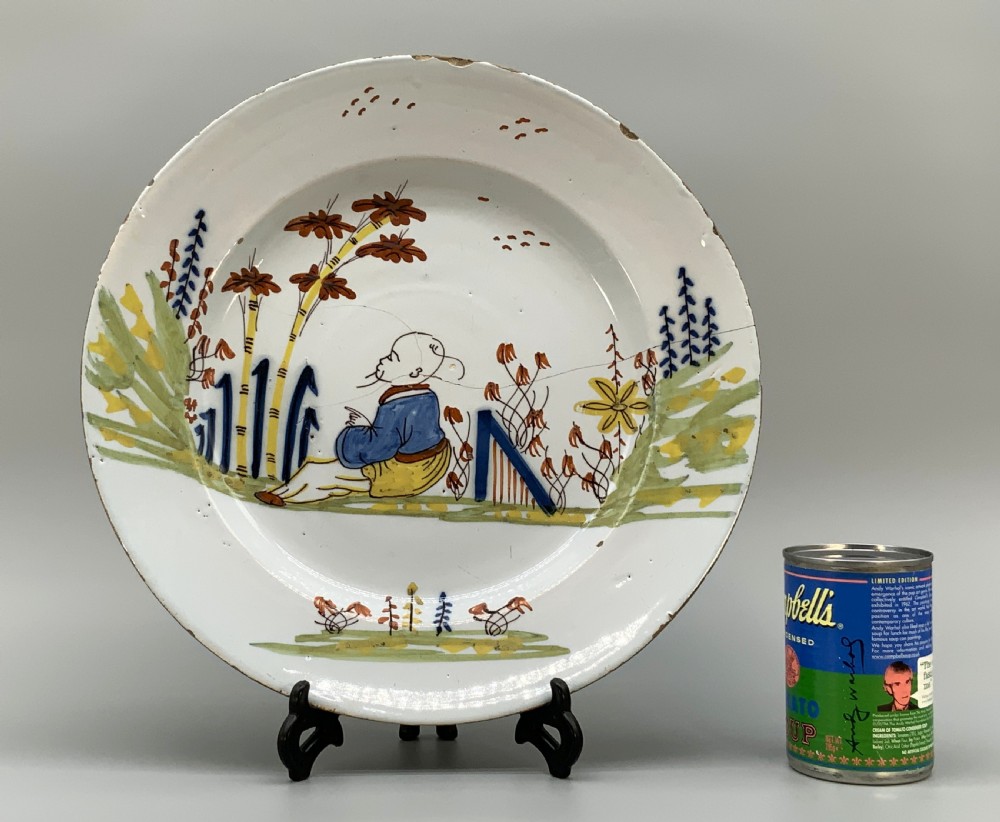 An eighteenth-century circular tin-glazed earthenware charger plate featuring a hand-painted polychrome Chinoiserie scene of a seated figure among bamboo and foliage. View II