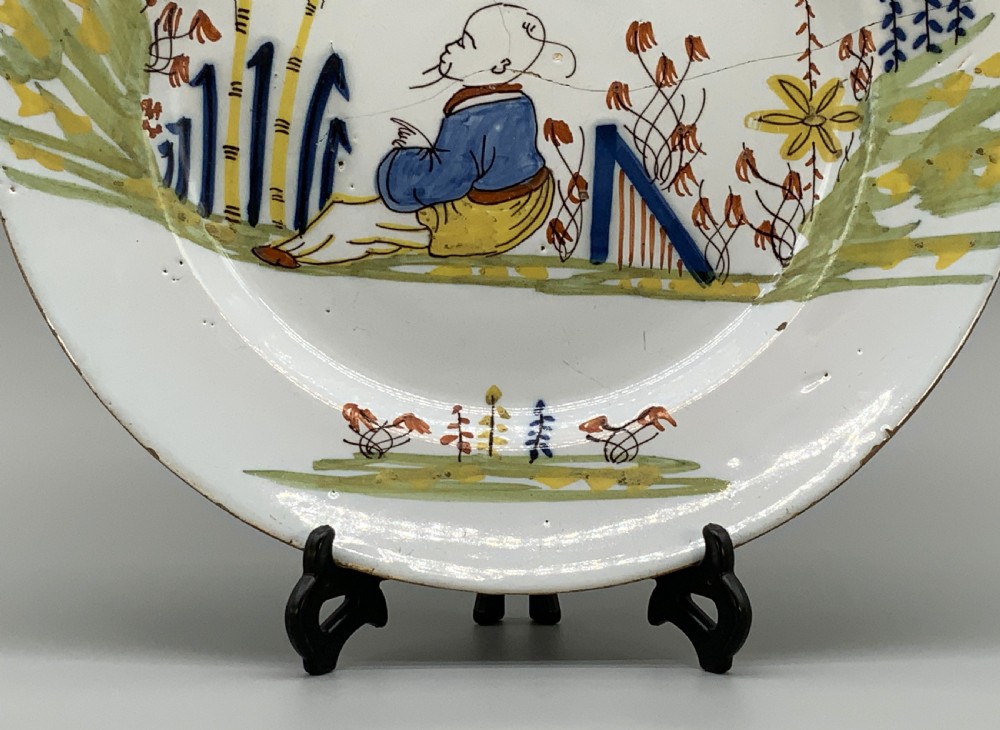 An eighteenth-century circular tin-glazed earthenware charger plate featuring a hand-painted polychrome Chinoiserie scene of a seated figure among bamboo and foliage. View VI