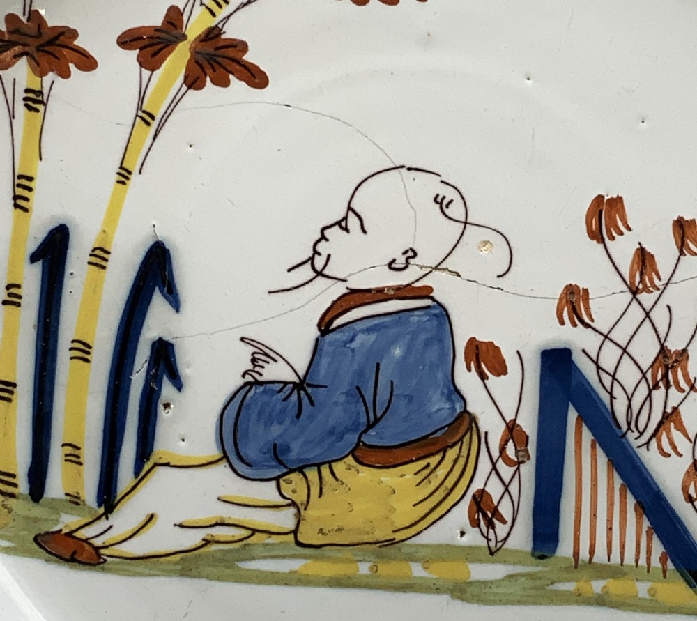 An eighteenth-century circular tin-glazed earthenware charger plate featuring a hand-painted polychrome Chinoiserie scene of a seated figure among bamboo and foliage. View IX