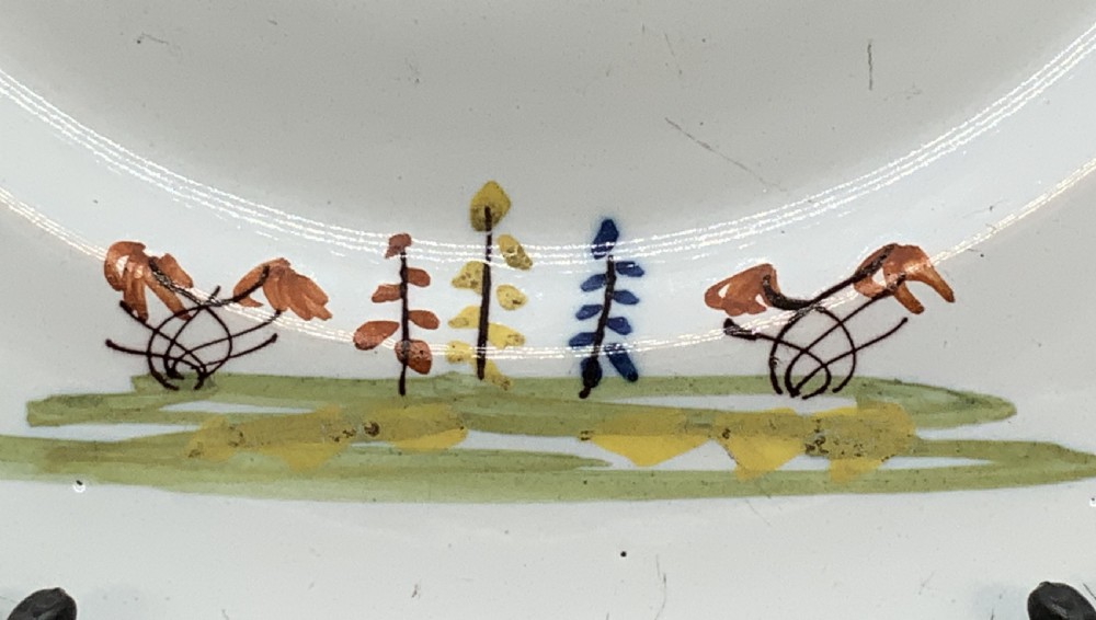 An eighteenth-century circular tin-glazed earthenware charger plate featuring a hand-painted polychrome Chinoiserie scene of a seated figure among bamboo and foliage. View X