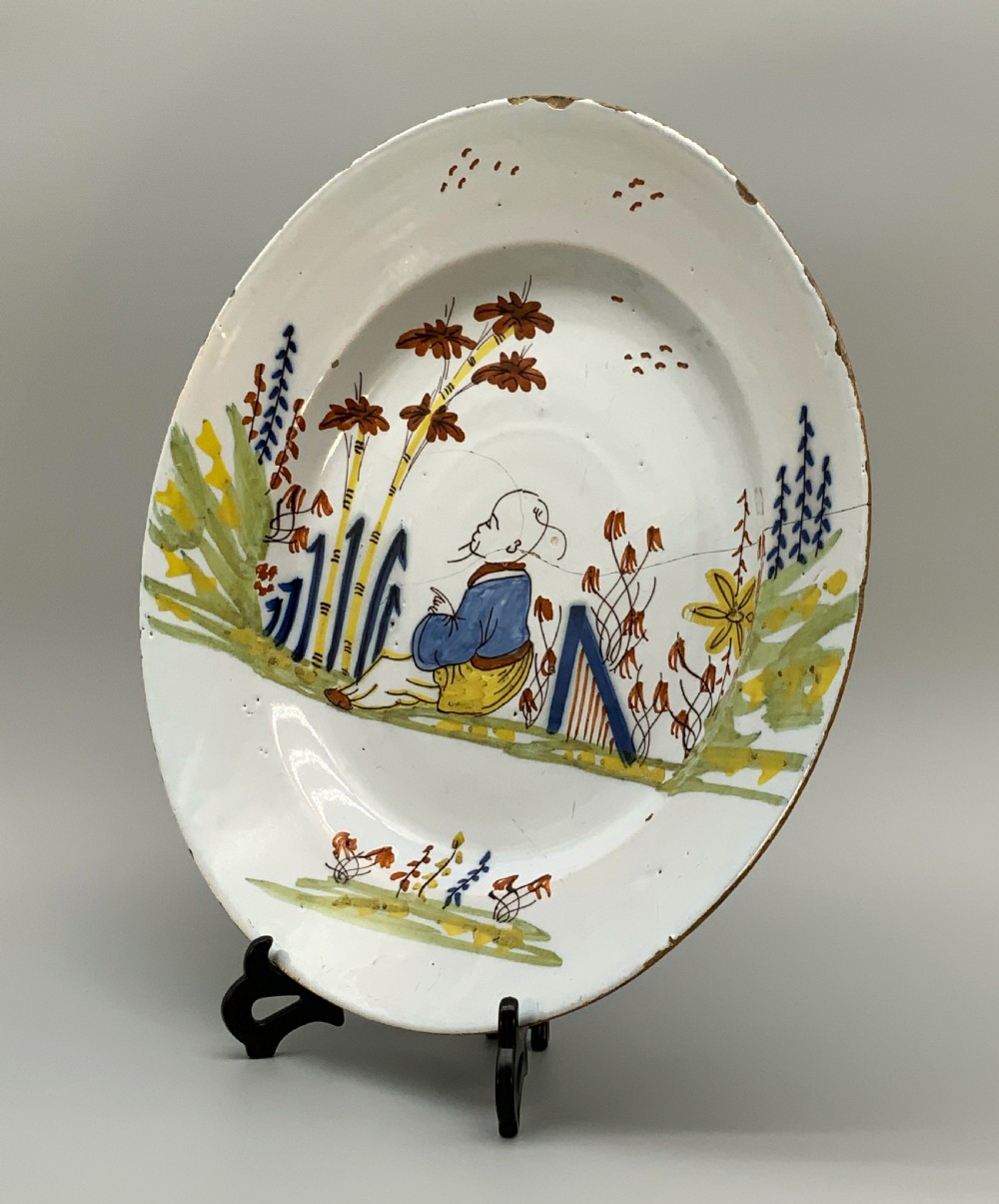 An eighteenth-century circular tin-glazed earthenware charger plate featuring a hand-painted polychrome Chinoiserie scene of a seated figure among bamboo and foliage. View XI