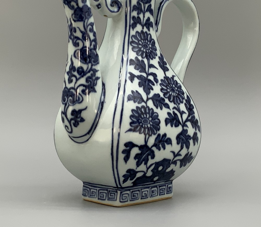 A blue and white porcelain ewer decorated with hand-painted floral foliage, featuring a high curved handle, slender curved spout, and a cover with a Foo dog finial. View XII