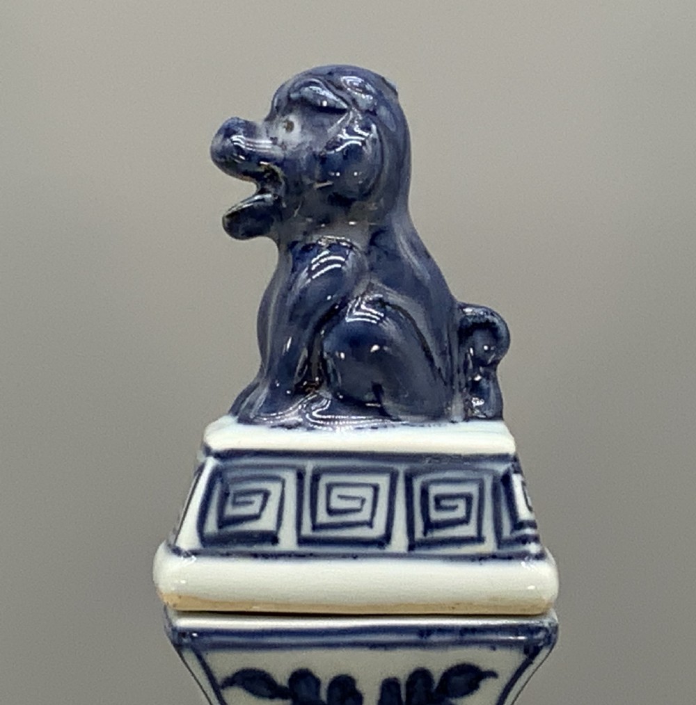A blue and white porcelain ewer decorated with hand-painted floral foliage, featuring a high curved handle, slender curved spout, and a cover with a Foo dog finial. View XV