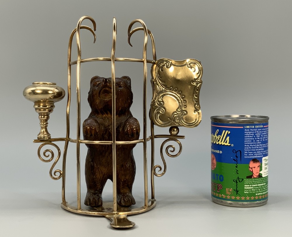 A 19th-century carved wooden bear standing upright inside a brass wire cage, attached to a brass candlestick holder on the left and an engraved brass vesta case on the right. View II