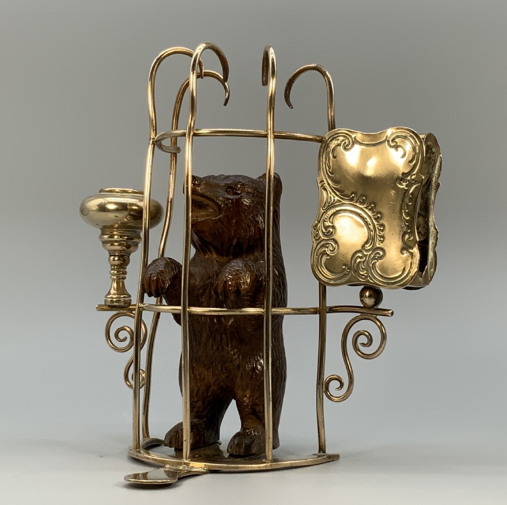 A 19th-century carved wooden bear standing upright inside a brass wire cage, attached to a brass candlestick holder on the left and an engraved brass vesta case on the right. View III