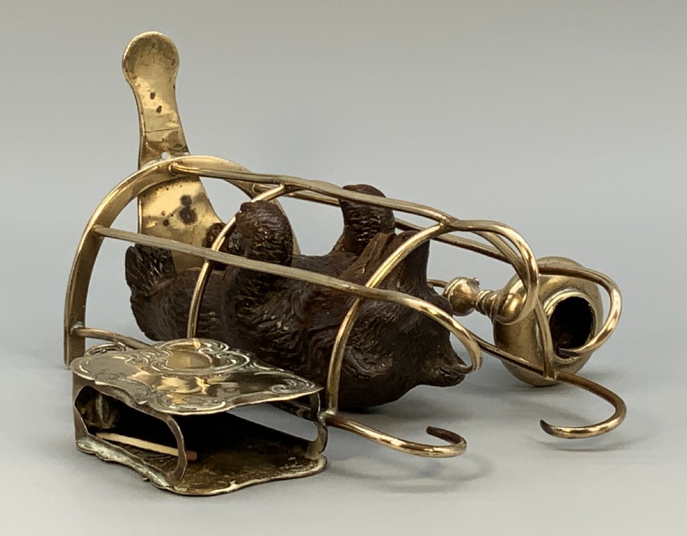 A 19th-century carved wooden bear standing upright inside a brass wire cage, attached to a brass candlestick holder on the left and an engraved brass vesta case on the right. View XIV