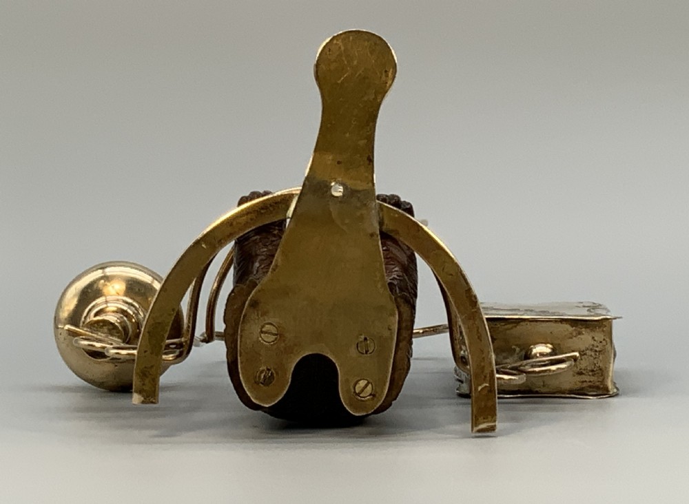 A 19th-century carved wooden bear standing upright inside a brass wire cage, attached to a brass candlestick holder on the left and an engraved brass vesta case on the right. View XV