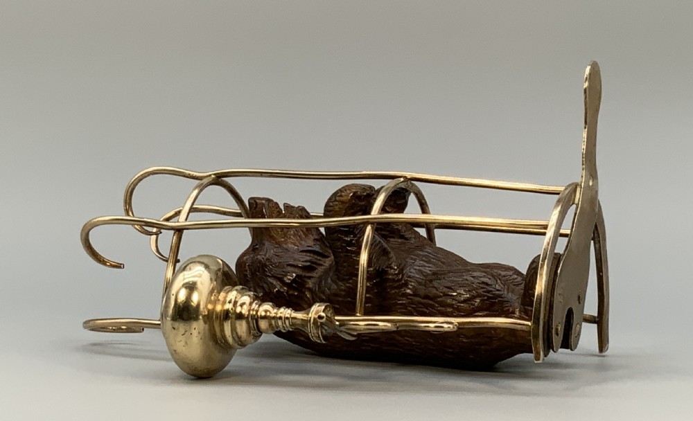 A 19th-century carved wooden bear standing upright inside a brass wire cage, attached to a brass candlestick holder on the left and an engraved brass vesta case on the right. View XVI