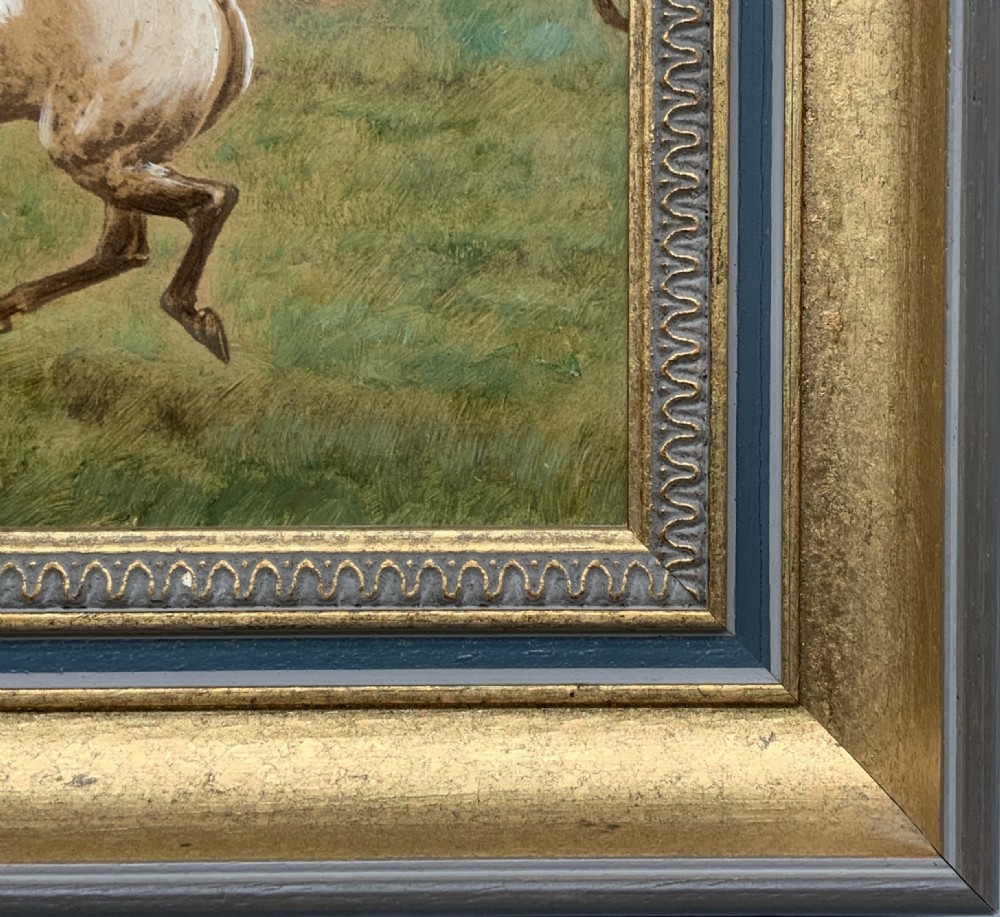 An oil painting on board depicting horseback riders navigating a grassy field, housed in a decorative gilded frame. View X