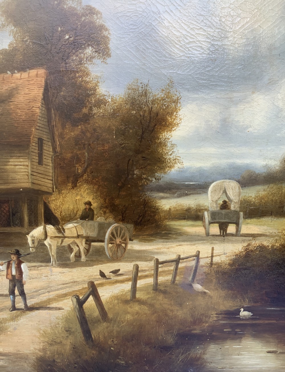 A 19th-century oil painting depicting a rural English village with horses, figures, and cottages on a dirt road, set in a carved gilded frame. View XIII