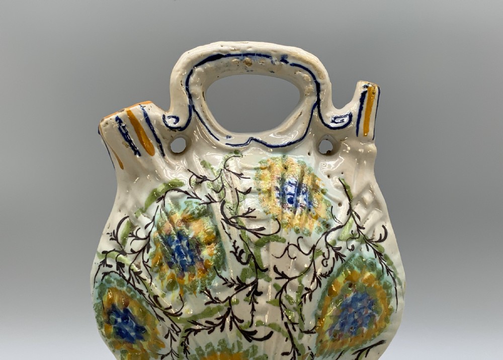 An 18th-century Italian polychrome majolica pilgrim flask formed as a scallop shell with an overhead handle, side loops, and hand-painted floral motifs in blue, yellow, and green over a cream glazed surface. View VIII