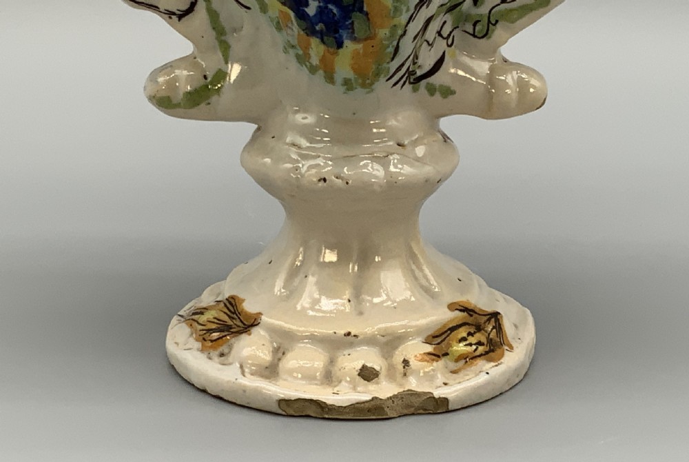 An 18th-century Italian polychrome majolica pilgrim flask formed as a scallop shell with an overhead handle, side loops, and hand-painted floral motifs in blue, yellow, and green over a cream glazed surface. View X