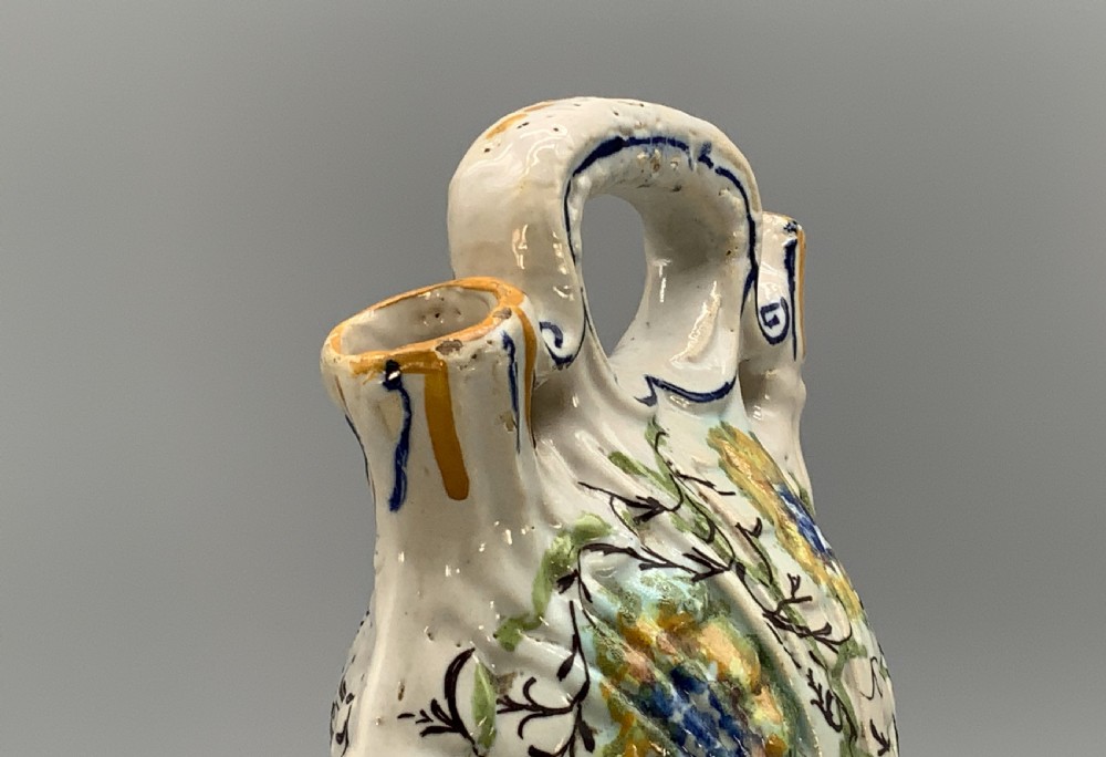 An 18th-century Italian polychrome majolica pilgrim flask formed as a scallop shell with an overhead handle, side loops, and hand-painted floral motifs in blue, yellow, and green over a cream glazed surface. View XI