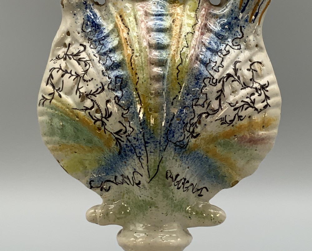 An 18th-century Italian polychrome majolica pilgrim flask formed as a scallop shell with an overhead handle, side loops, and hand-painted floral motifs in blue, yellow, and green over a cream glazed surface. View XIII