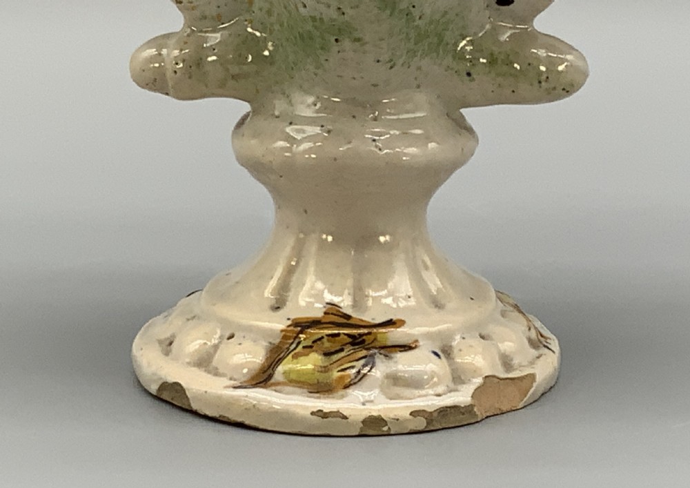 An 18th-century Italian polychrome majolica pilgrim flask formed as a scallop shell with an overhead handle, side loops, and hand-painted floral motifs in blue, yellow, and green over a cream glazed surface. View XIV