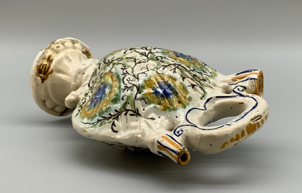 An 18th-century Italian polychrome majolica pilgrim flask formed as a scallop shell with an overhead handle, side loops, and hand-painted floral motifs in blue, yellow, and green over a cream glazed surface. View XV