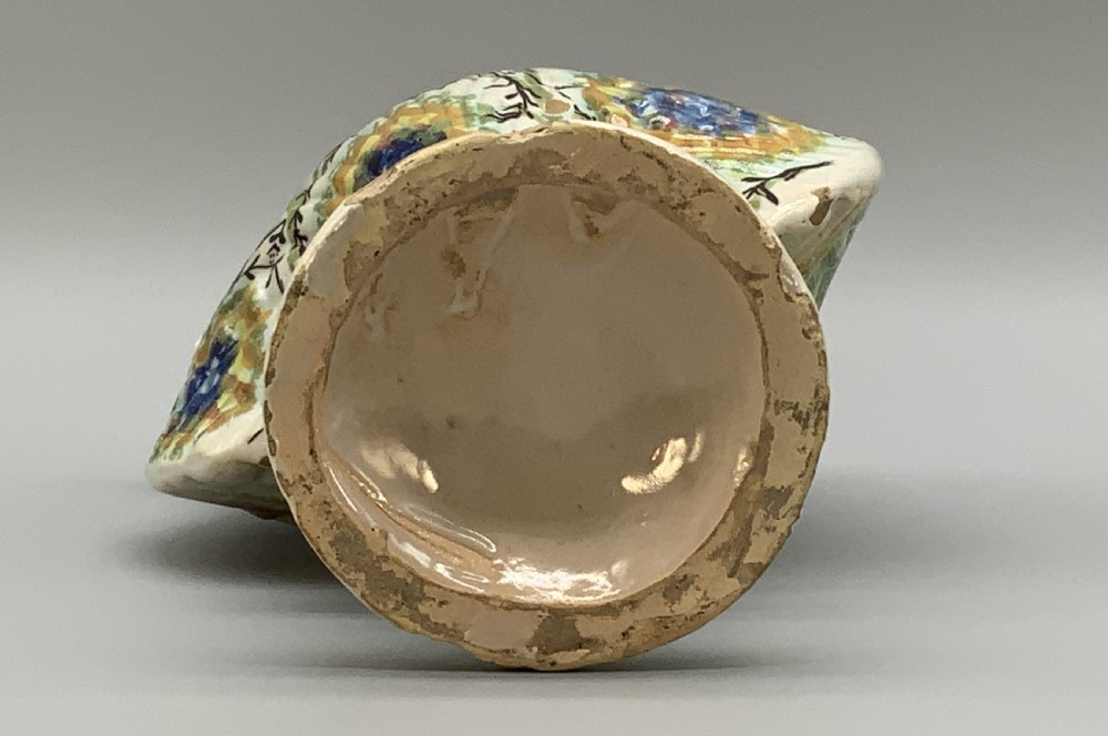 An 18th-century Italian polychrome majolica pilgrim flask formed as a scallop shell with an overhead handle, side loops, and hand-painted floral motifs in blue, yellow, and green over a cream glazed surface. View XVII