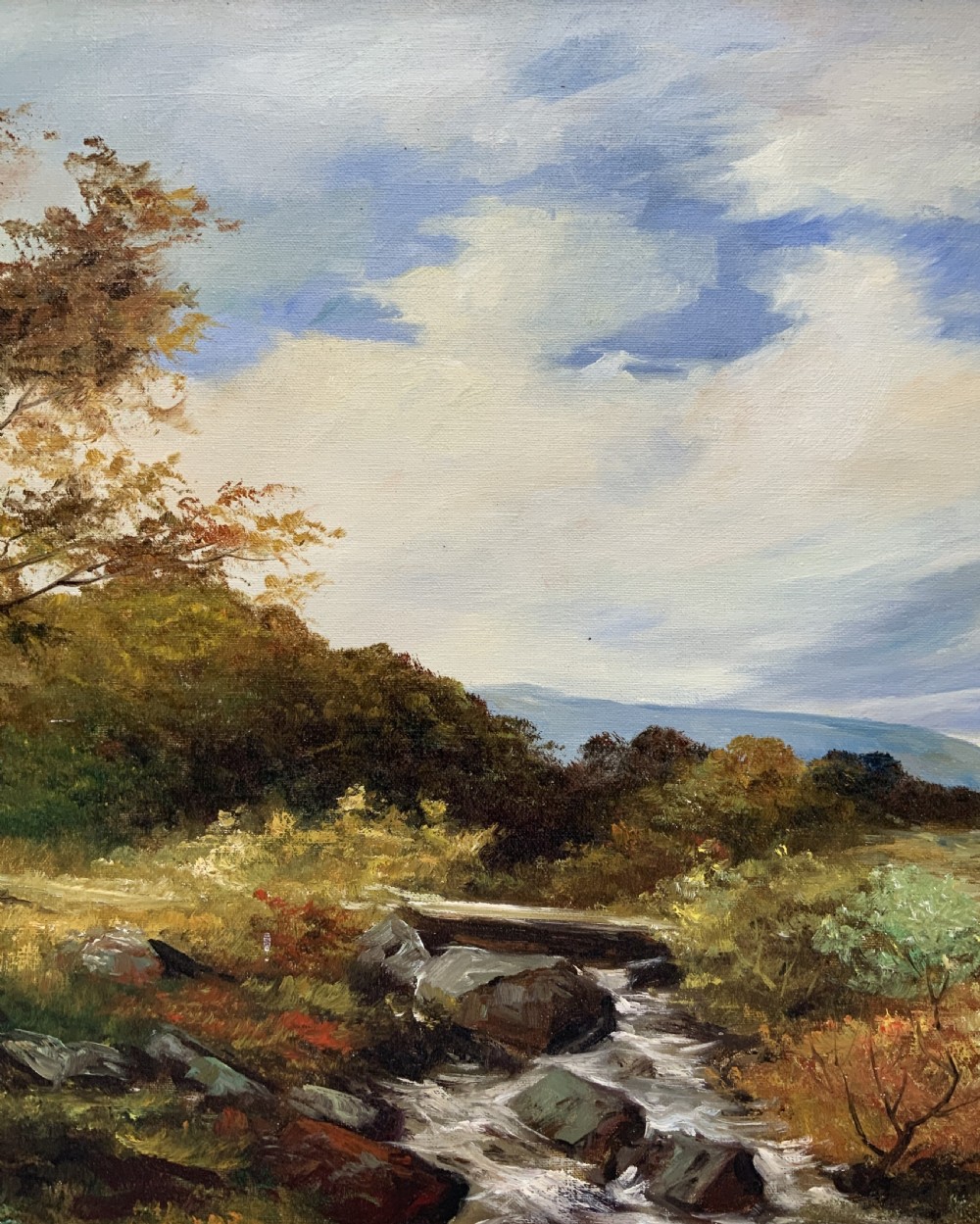 An oil painting on canvas depicting an autumnal countryside landscape with a running stream, trees, distant hills, and a gilded ornate wooden frame with a fabric slip. View V