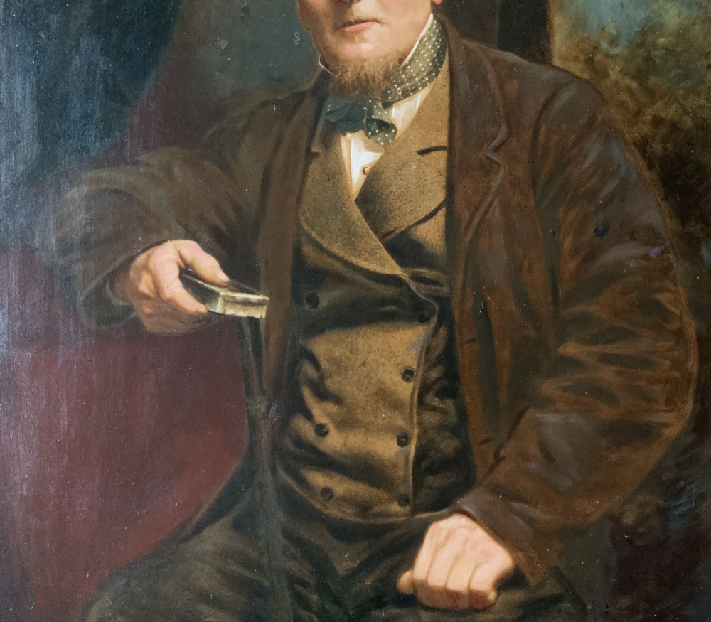 A 19th-century oil painting depicting a seated gentleman in a brown coat and waistcoat holding a small book, encased in an ornate gilded frame. View VII