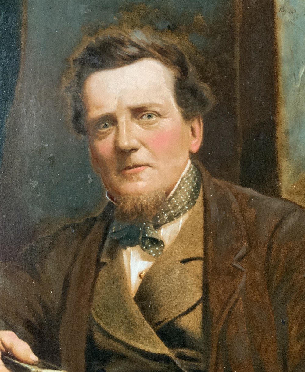 A 19th-century oil painting depicting a seated gentleman in a brown coat and waistcoat holding a small book, encased in an ornate gilded frame. View X