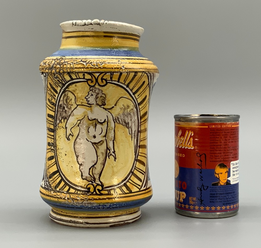 A waisted cylindrical tin-glazed majolica albarello jar decorated in yellow, blue, and dark brown hand-painted pigments featuring a central winged figure motif. View III