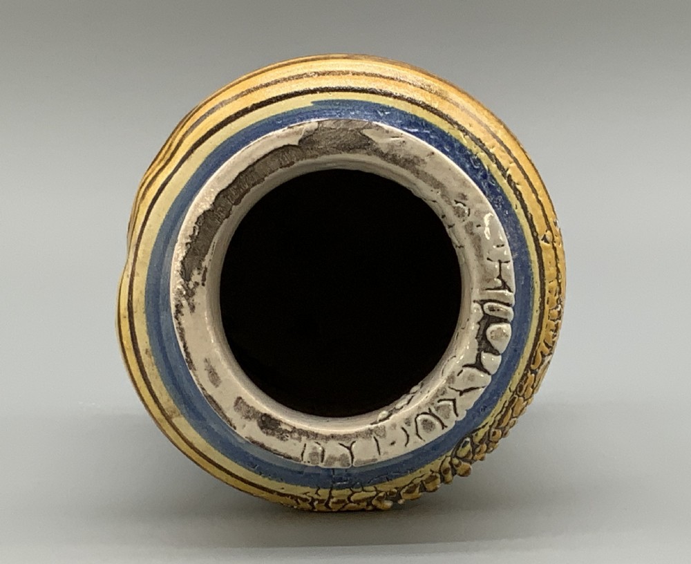 A waisted cylindrical tin-glazed majolica albarello jar decorated in yellow, blue, and dark brown hand-painted pigments featuring a central winged figure motif. View XII
