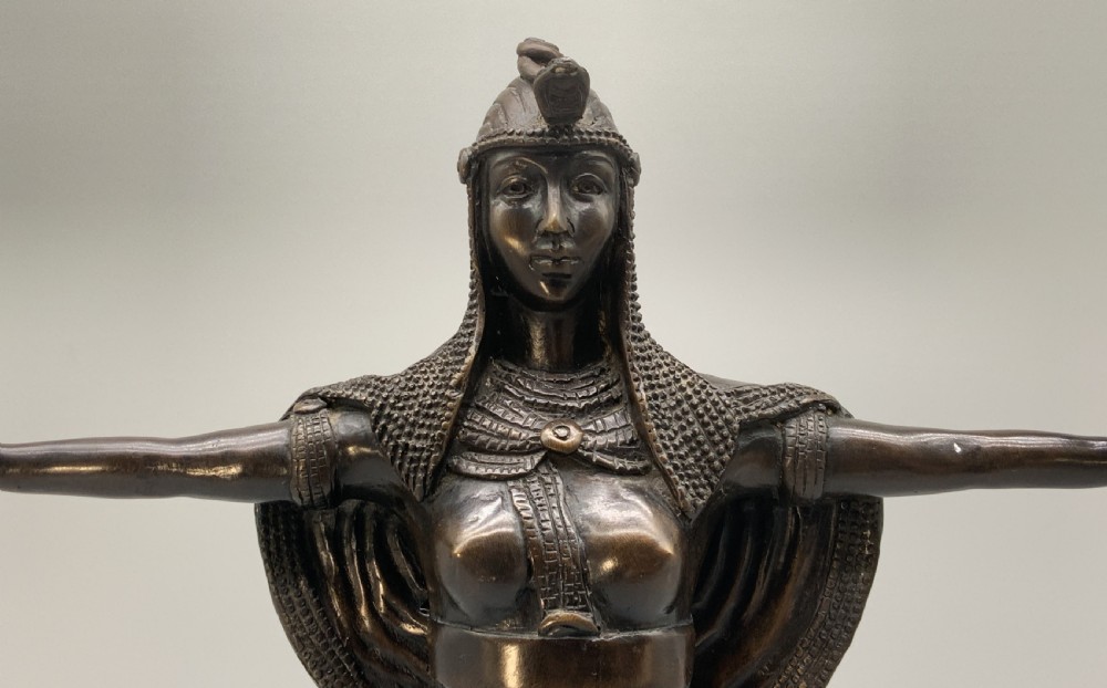 A patinated bronze Egyptian Revival candelabra featuring a female figure with outstretched arms holding two candle sockets, standing on a decorated triangular base. View V