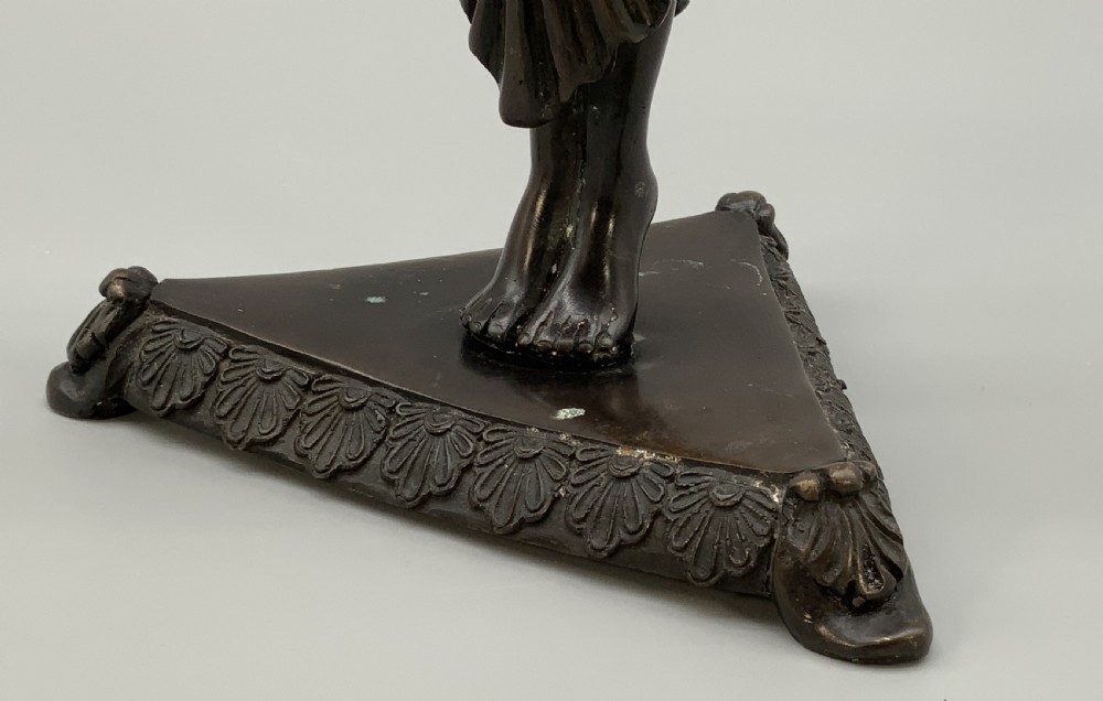 A patinated bronze Egyptian Revival candelabra featuring a female figure with outstretched arms holding two candle sockets, standing on a decorated triangular base. View XII