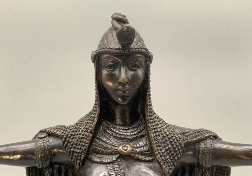 A patinated bronze Egyptian Revival candelabra featuring a female figure with outstretched arms holding two candle sockets, standing on a decorated triangular base. View XIII