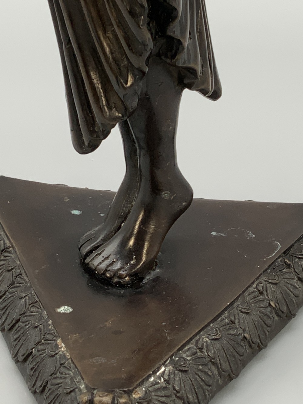 A patinated bronze Egyptian Revival candelabra featuring a female figure with outstretched arms holding two candle sockets, standing on a decorated triangular base. View XVII