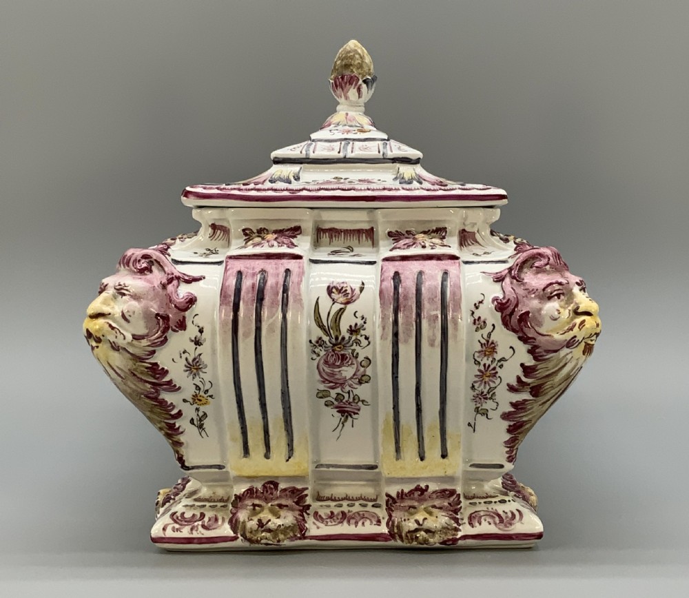 An antique French faience covered soup tureen featuring hand-painted pastoral scenes in manganese purple, moulded lion mask side handles, and a stepped lid with a finial. View V