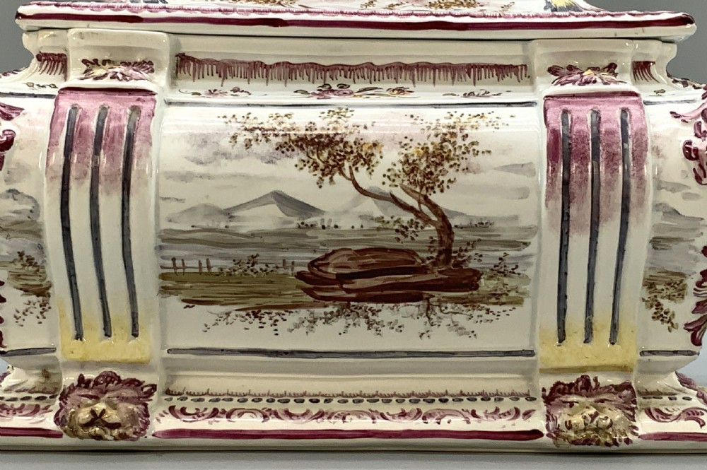 An antique French faience covered soup tureen featuring hand-painted pastoral scenes in manganese purple, moulded lion mask side handles, and a stepped lid with a finial. View VII