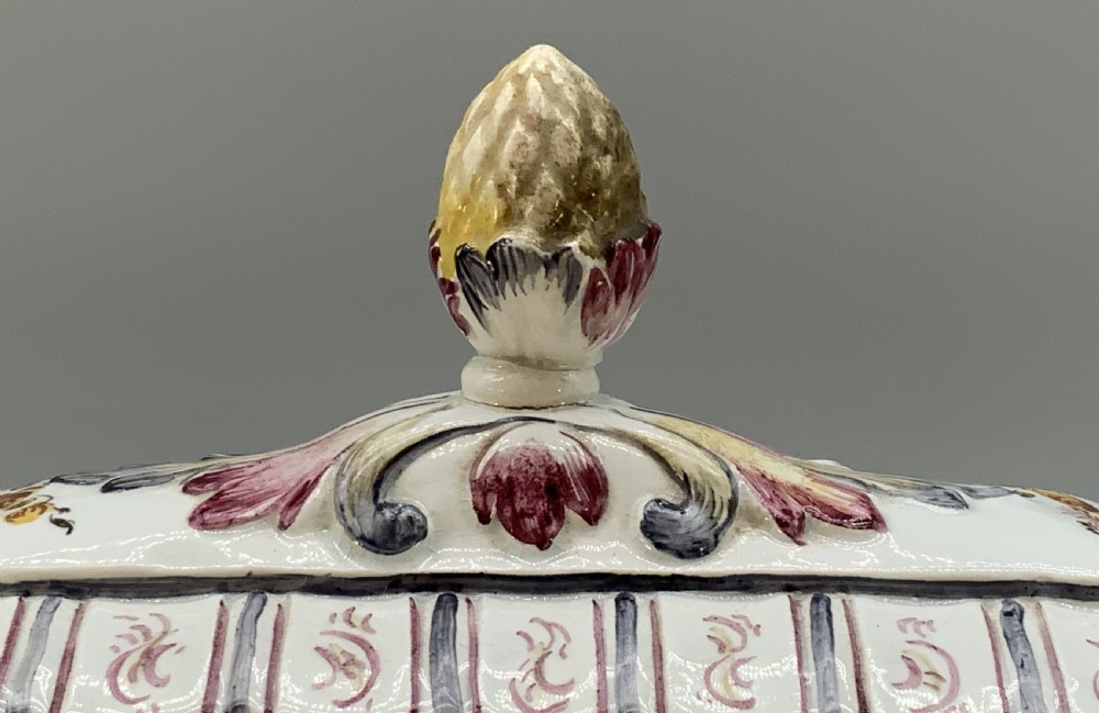 An antique French faience covered soup tureen featuring hand-painted pastoral scenes in manganese purple, moulded lion mask side handles, and a stepped lid with a finial. View IX