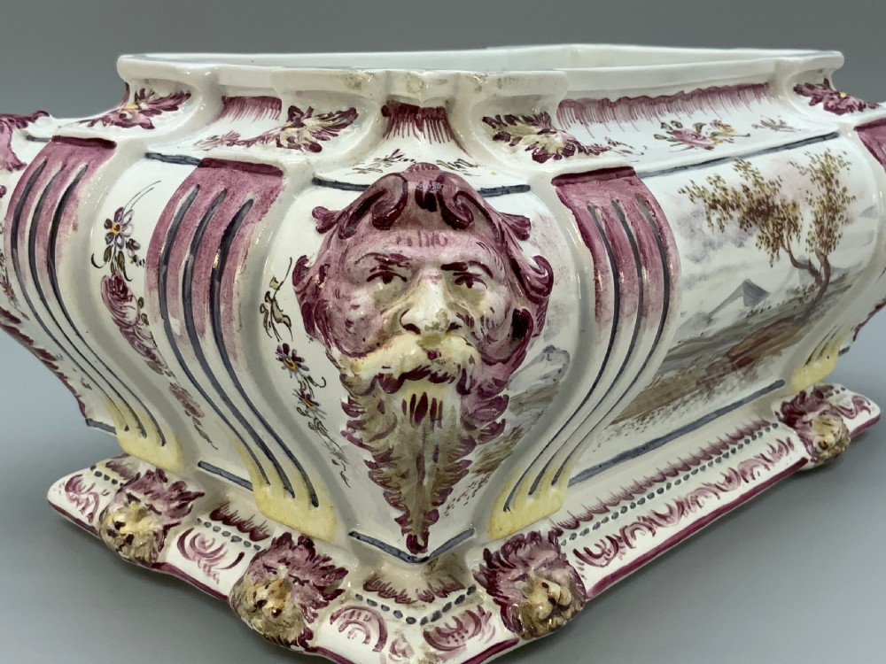 An antique French faience covered soup tureen featuring hand-painted pastoral scenes in manganese purple, moulded lion mask side handles, and a stepped lid with a finial. View XII
