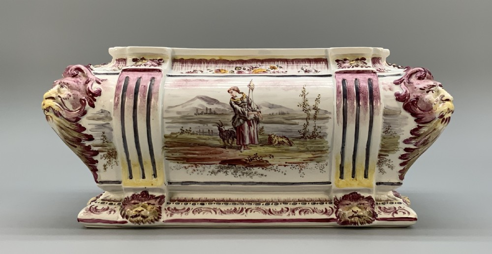 An antique French faience covered soup tureen featuring hand-painted pastoral scenes in manganese purple, moulded lion mask side handles, and a stepped lid with a finial. View XIV