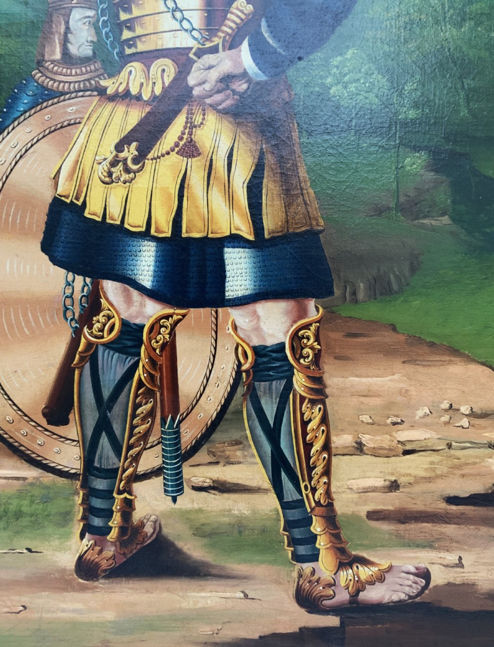 An antique framed oil painting depicting Goliath clad in ornate gold and blue armour holding a spear, with David standing across a stream in the background. View X